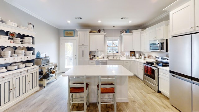 kitchen with white cabinetry, a kitchen island, stainless steel appliances, and light wood-type flooring