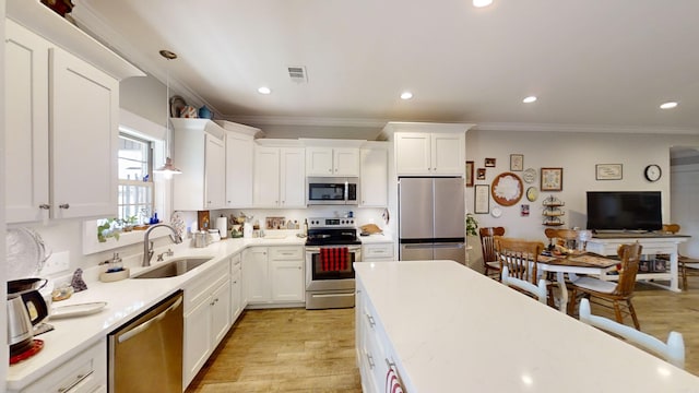 kitchen with light wood-style flooring, stainless steel appliances, light countertops, white cabinetry, and a sink