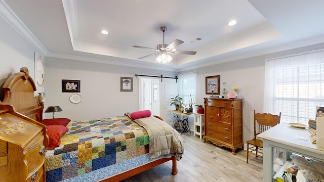 bedroom with ornamental molding, a tray ceiling, ceiling fan, a barn door, and light hardwood / wood-style floors