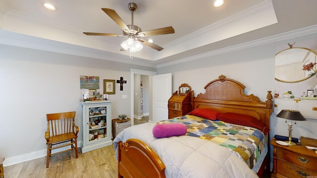 bedroom with a tray ceiling, ceiling fan, light hardwood / wood-style floors, and ornamental molding