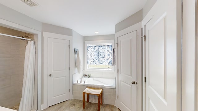 bathroom featuring plus walk in shower and hardwood / wood-style floors