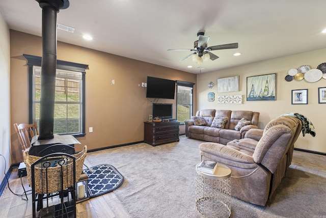 living room with light hardwood / wood-style flooring, a wood stove, and ceiling fan