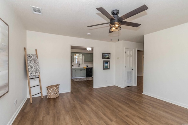 unfurnished living room with dark hardwood / wood-style floors, ceiling fan, and a textured ceiling