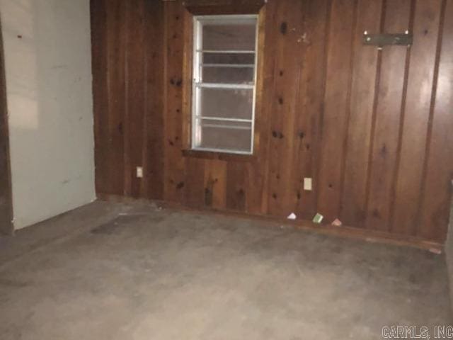 unfurnished room featuring wooden walls