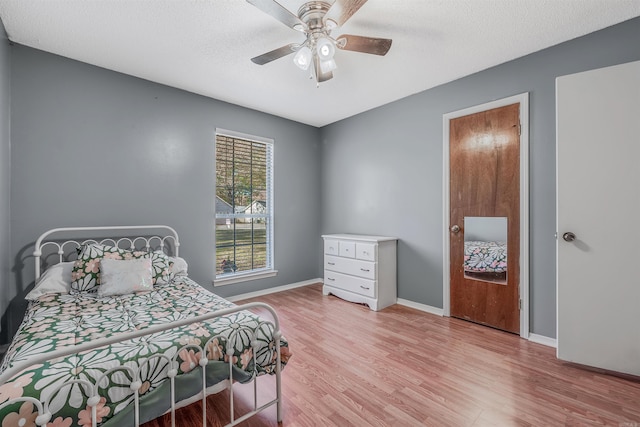 bedroom featuring ceiling fan, light hardwood / wood-style flooring, and a textured ceiling