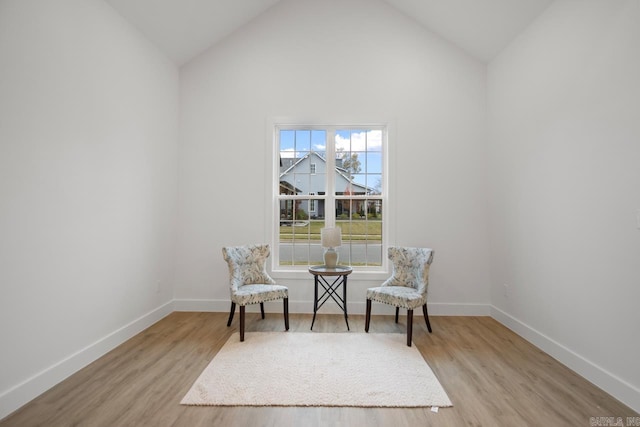 sitting room with light wood-type flooring and high vaulted ceiling