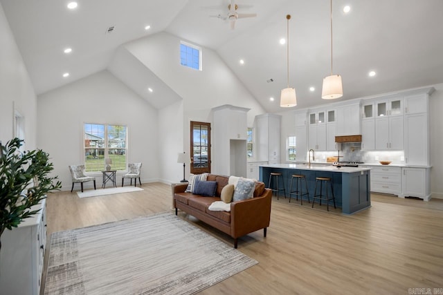 living room featuring ceiling fan, sink, high vaulted ceiling, and light hardwood / wood-style floors