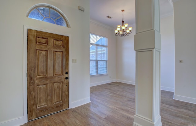 entryway with crown molding, light hardwood / wood-style flooring, and a chandelier