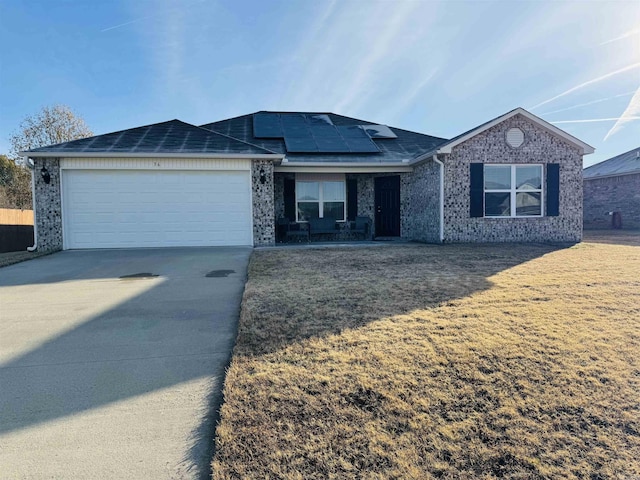 single story home featuring solar panels, a garage, and a front lawn