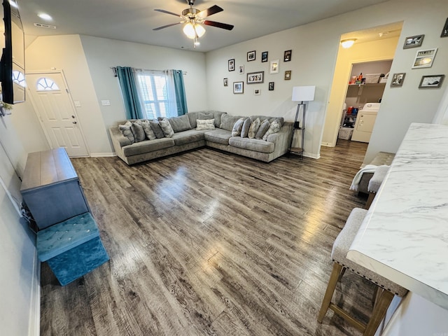 living room with ceiling fan, washer / dryer, and dark wood-type flooring