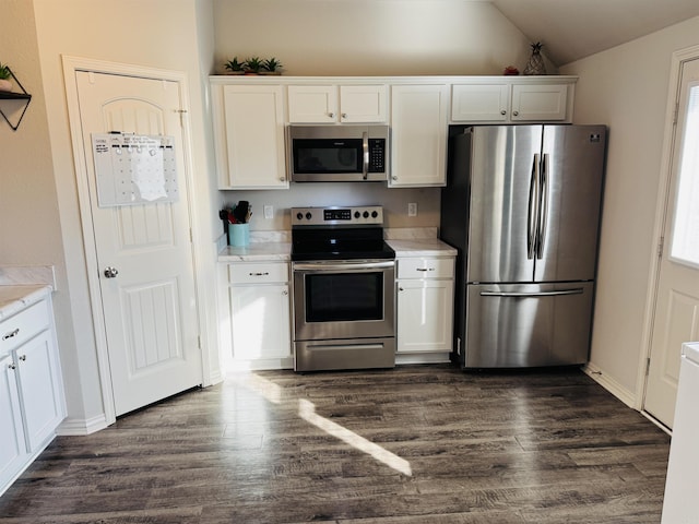 kitchen featuring dark hardwood / wood-style flooring, white cabinetry, stainless steel appliances, and vaulted ceiling