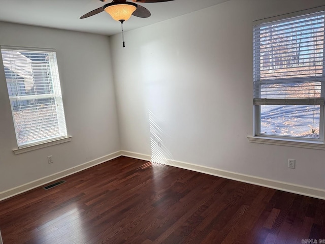 empty room featuring plenty of natural light, dark hardwood / wood-style floors, and ceiling fan