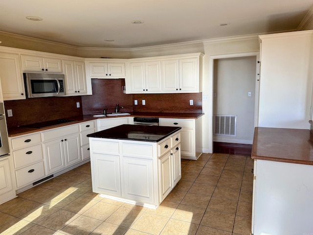 kitchen with white cabinets, a kitchen island, light tile patterned floors, and appliances with stainless steel finishes