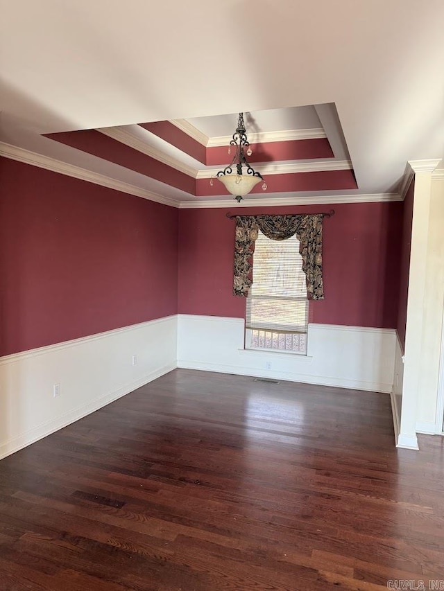 empty room featuring a tray ceiling, crown molding, and dark hardwood / wood-style floors