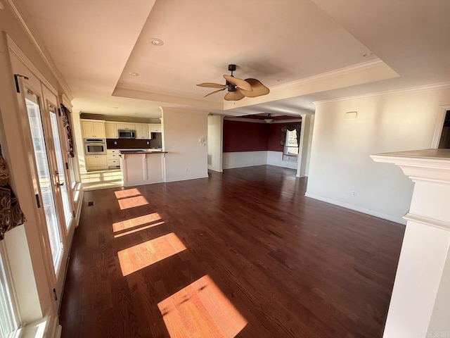 unfurnished living room featuring dark hardwood / wood-style floors, ceiling fan, a raised ceiling, and ornamental molding