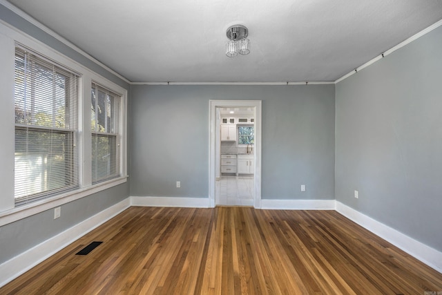 empty room featuring hardwood / wood-style flooring, crown molding, and sink