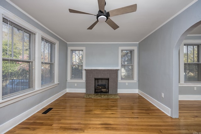 unfurnished living room with a wealth of natural light, a fireplace, ceiling fan, and hardwood / wood-style flooring