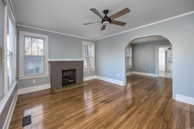 unfurnished living room with hardwood / wood-style flooring, a brick fireplace, ceiling fan, and ornamental molding