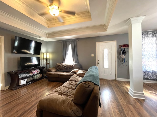 living room featuring ornate columns, ceiling fan, a tray ceiling, hardwood / wood-style flooring, and ornamental molding