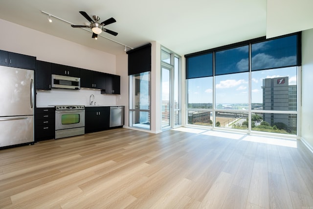 kitchen with plenty of natural light, floor to ceiling windows, stainless steel appliances, and light hardwood / wood-style flooring