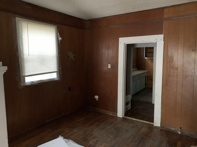 spare room featuring wooden walls and dark wood-type flooring