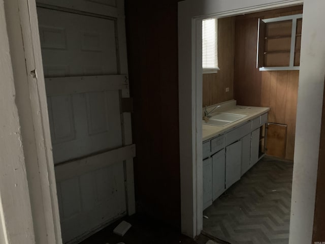 bathroom featuring wooden walls, sink, and parquet flooring