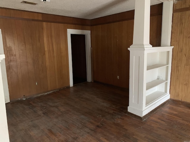 interior space with a textured ceiling, wood walls, and dark hardwood / wood-style floors