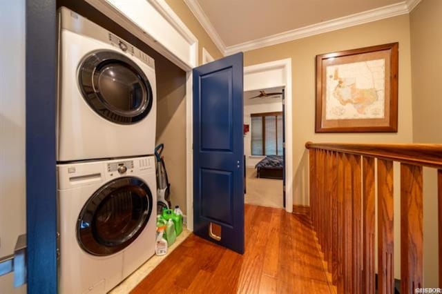 washroom featuring hardwood / wood-style floors, crown molding, and stacked washer and dryer