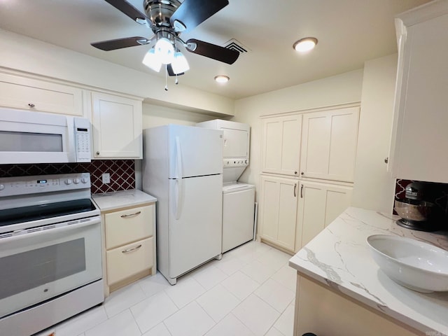 kitchen with sink, stacked washing maching and dryer, light stone counters, backsplash, and white appliances