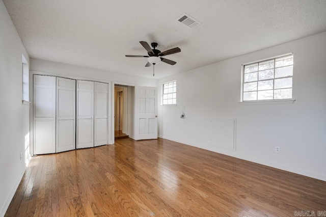 unfurnished bedroom featuring multiple windows, ceiling fan, light hardwood / wood-style floors, and a textured ceiling