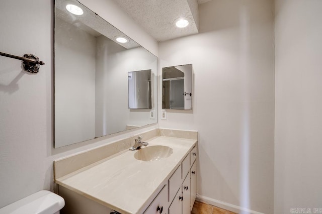 bathroom with tile patterned flooring, vanity, toilet, and a textured ceiling