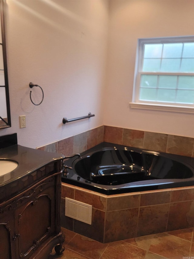 bathroom with tiled bath and vanity