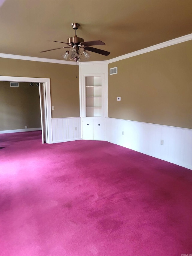 carpeted spare room with ceiling fan, built in features, and crown molding