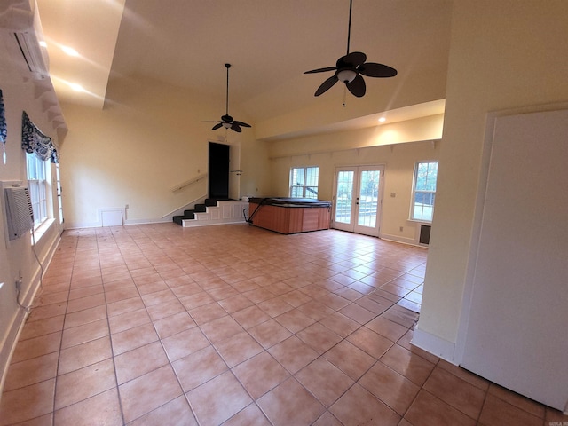 unfurnished living room featuring light tile patterned floors, ceiling fan, a healthy amount of sunlight, french doors, and high vaulted ceiling