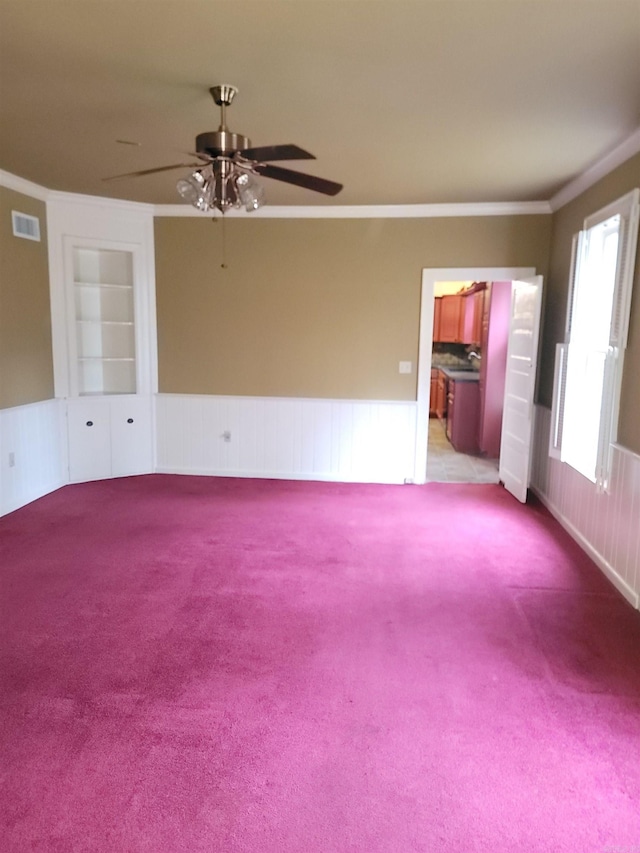 spare room with light carpet, ceiling fan, built in features, and ornamental molding