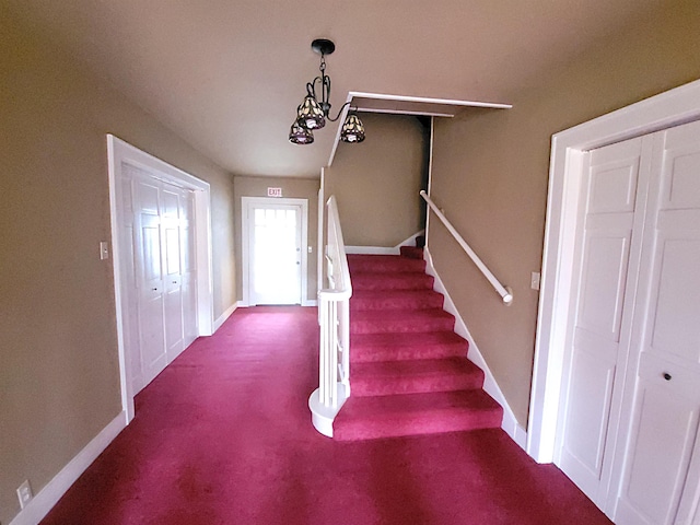 stairs with carpet floors and an inviting chandelier