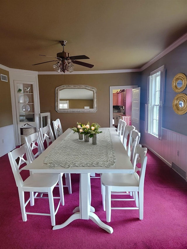 dining room featuring ceiling fan, crown molding, and dark colored carpet