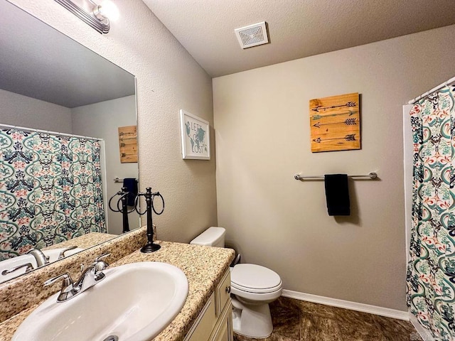 bathroom with vanity, toilet, and a textured ceiling