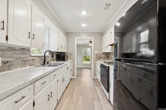 kitchen with white appliances, white cabinetry, a wealth of natural light, and sink