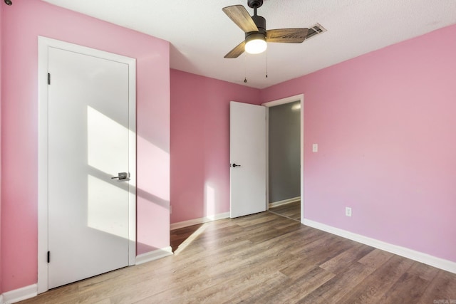 unfurnished bedroom featuring a textured ceiling, light wood-type flooring, a closet, and ceiling fan