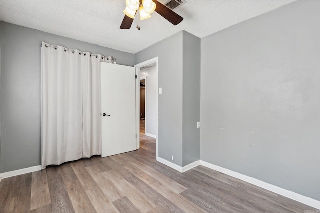 unfurnished bedroom with a textured ceiling, light wood-type flooring, and ceiling fan