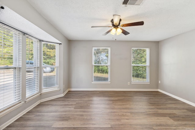 empty room featuring hardwood / wood-style flooring, ceiling fan, a textured ceiling, and a wealth of natural light