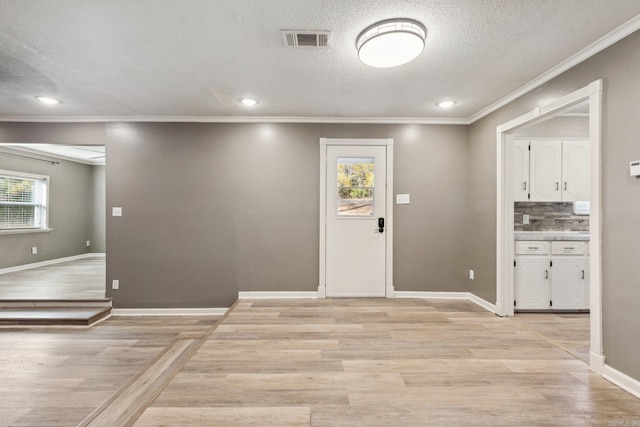 foyer entrance featuring a healthy amount of sunlight, ornamental molding, a textured ceiling, and light hardwood / wood-style flooring