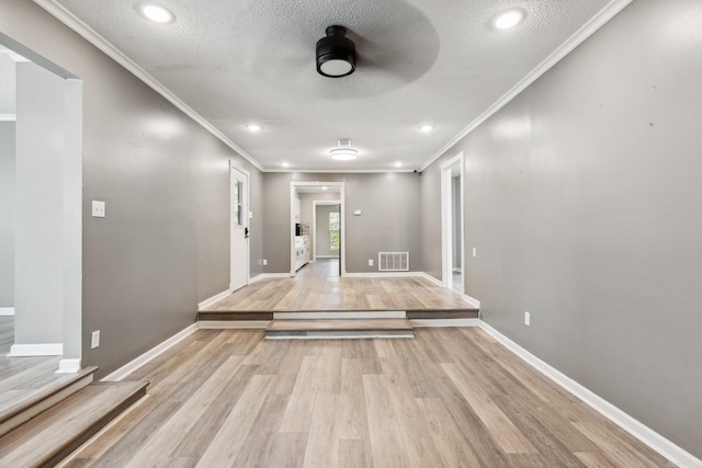 hallway featuring crown molding, light hardwood / wood-style flooring, and a textured ceiling