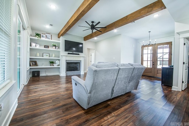 living room with ceiling fan with notable chandelier, dark hardwood / wood-style flooring, beamed ceiling, and french doors