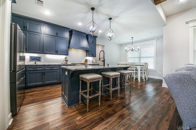 kitchen featuring a breakfast bar area, a kitchen island with sink, pendant lighting, and custom range hood