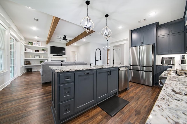 kitchen featuring pendant lighting, a kitchen island with sink, ceiling fan with notable chandelier, appliances with stainless steel finishes, and dark hardwood / wood-style flooring