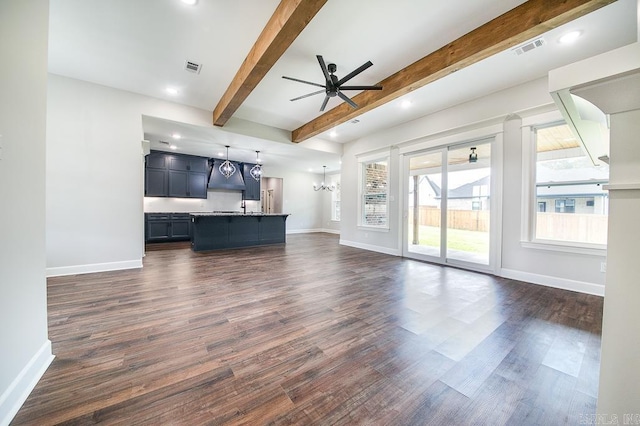 unfurnished living room with beamed ceiling, ceiling fan with notable chandelier, and dark wood-type flooring