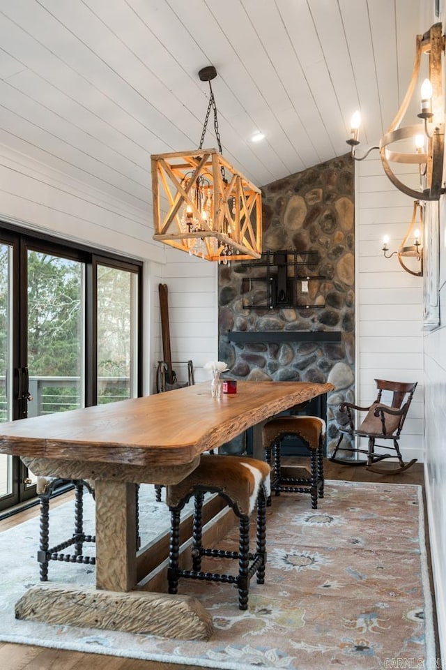 dining room featuring hardwood / wood-style flooring, vaulted ceiling, a notable chandelier, and wood walls