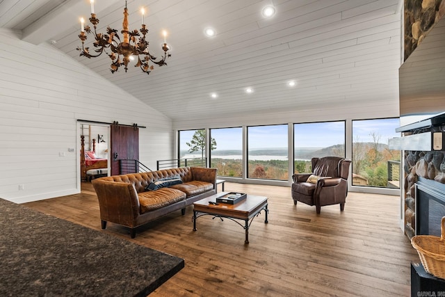 living room with an inviting chandelier, a barn door, high vaulted ceiling, a fireplace, and hardwood / wood-style flooring